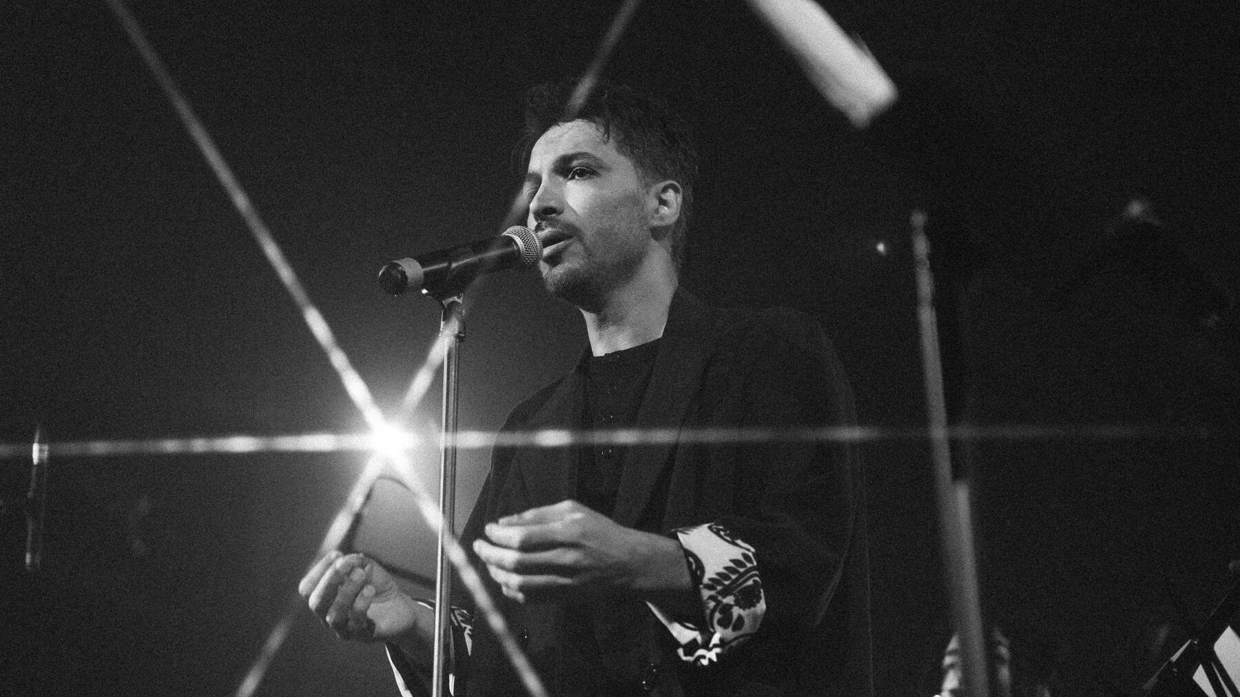 Dariush Azar au chant sur scène, photographie en noir et blanc.